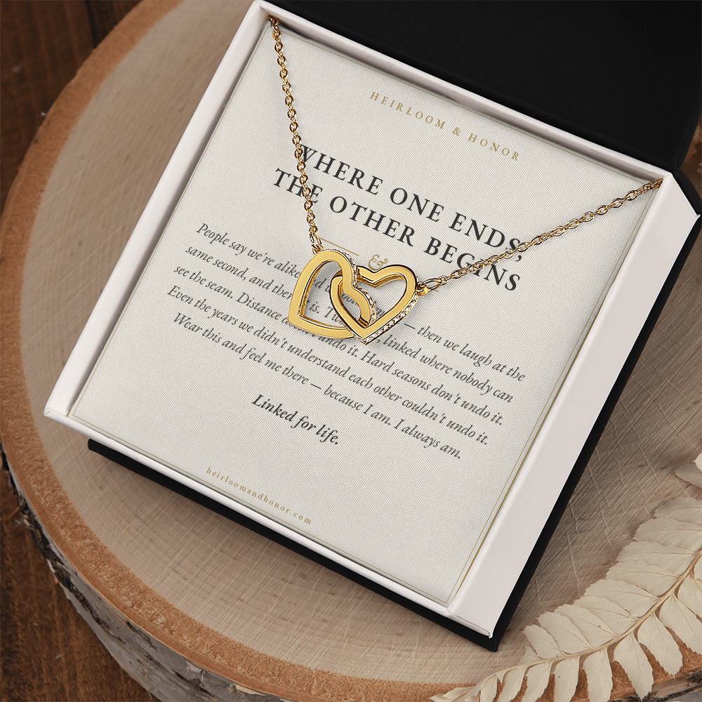 Interlocking hearts necklace and message card in open gift box on rustic wood