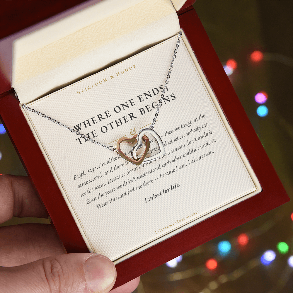 Hand holding mahogany box with interlocking hearts necklace by holiday lights